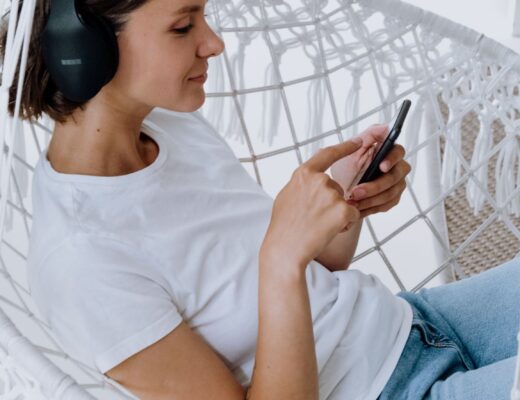 Woman sitting in chair with headphones listening to her phone