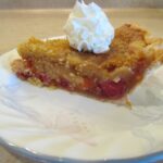 a slice of cherry peach pie with a dollop of cream