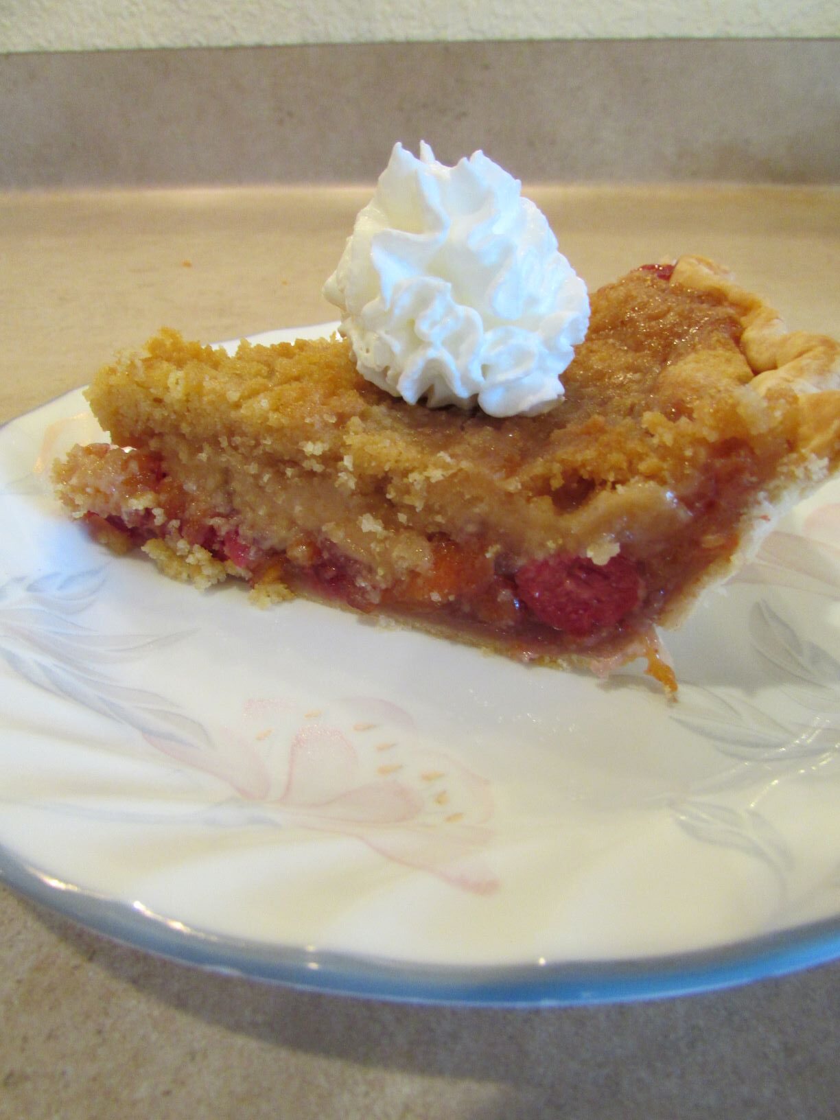a slice of cherry peach pie with a dollop of cream