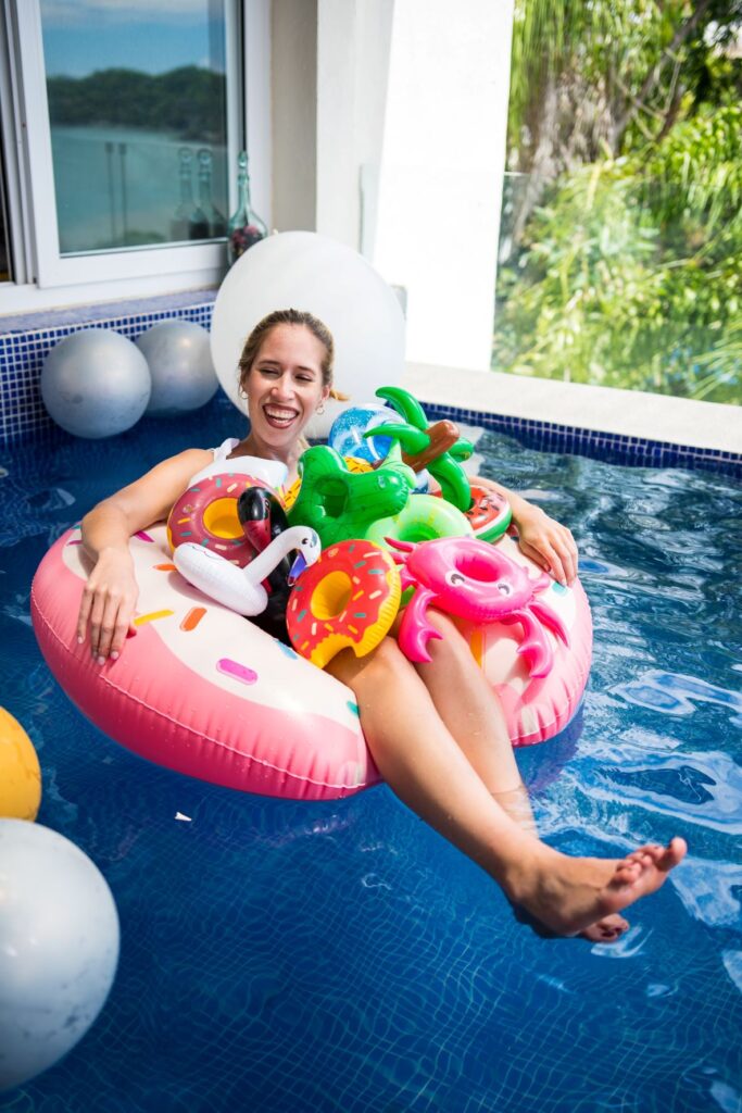 woman in pool with inflatable pool toys on her